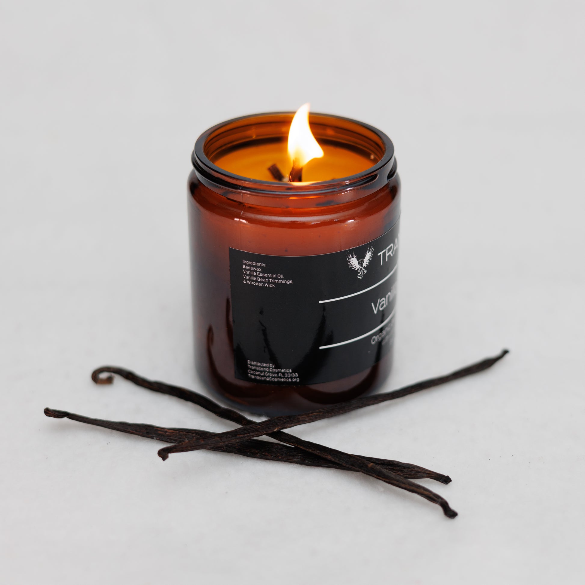 Image showing the ingredient list on the Transcend Cosmetics Vanilla Vacay Organic Beeswax Candle, in an amber glass jar with a wooden wick, burning with a warm flame, surrounded by vanilla beans, highlighting its natural and soothing ingredients.
Ingredients are: Beeswax, Vanilla Essential Oil, Vanilla Beans, & Wooden Wick. 