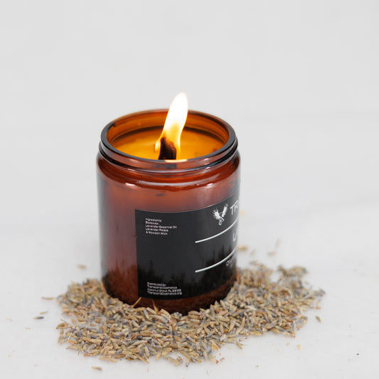 Image showing the ingredient list on the Transcend Cosmetics Lavitate Organic Beeswax Candle, in an amber glass jar with a wooden wick, burning with a warm flame, surrounded by dried lavender petals, highlighting its natural and soothing ingredients.
Ingredients are: Beeswax, Lavender Essential Oil, Lavender Petals, & Wooden Wick. 